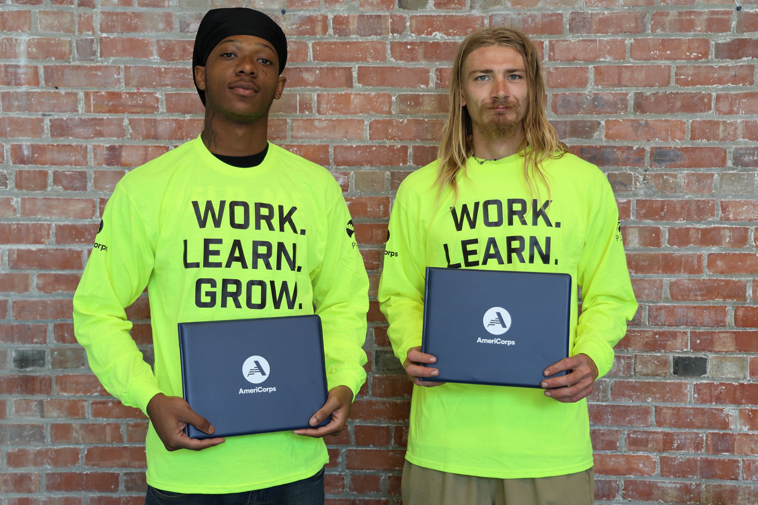 Two men holding certificates for PeoriaCorps graduation.