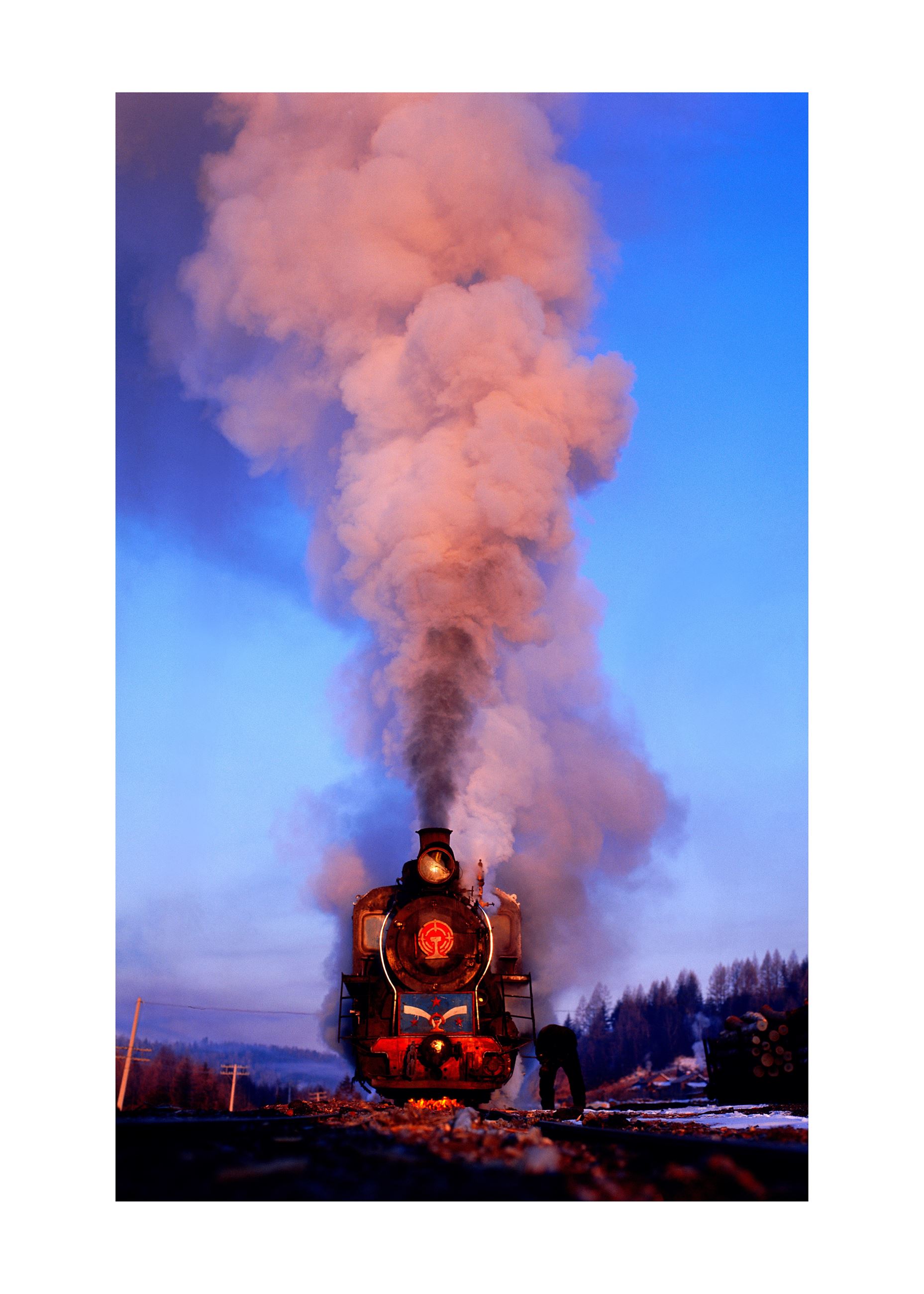 Photograph of a steam locomotive in motion, smoke billowing of the the chimney.