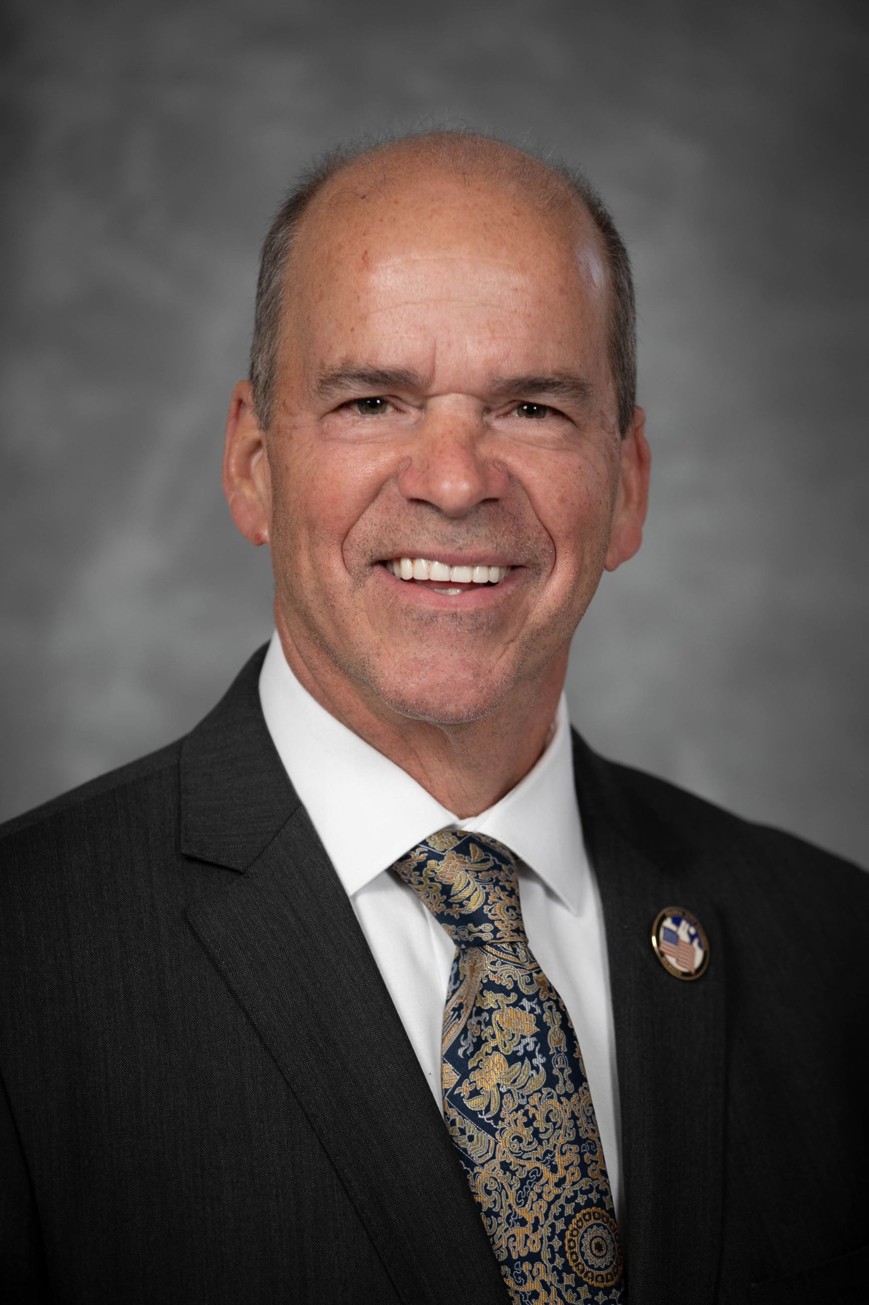 Headshot of a man in a coat and tie.
