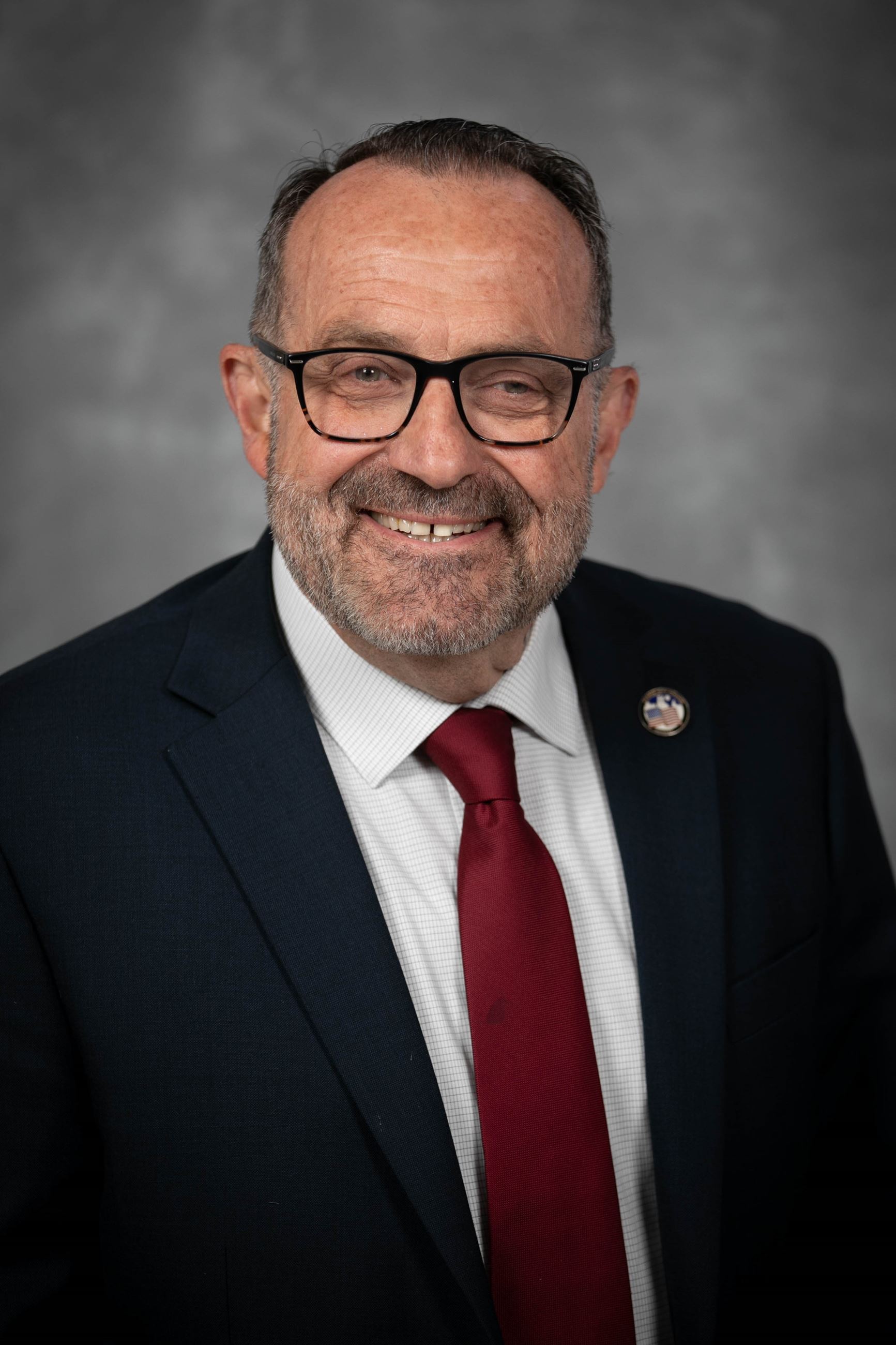 Headshot of a man in a coat and tie.