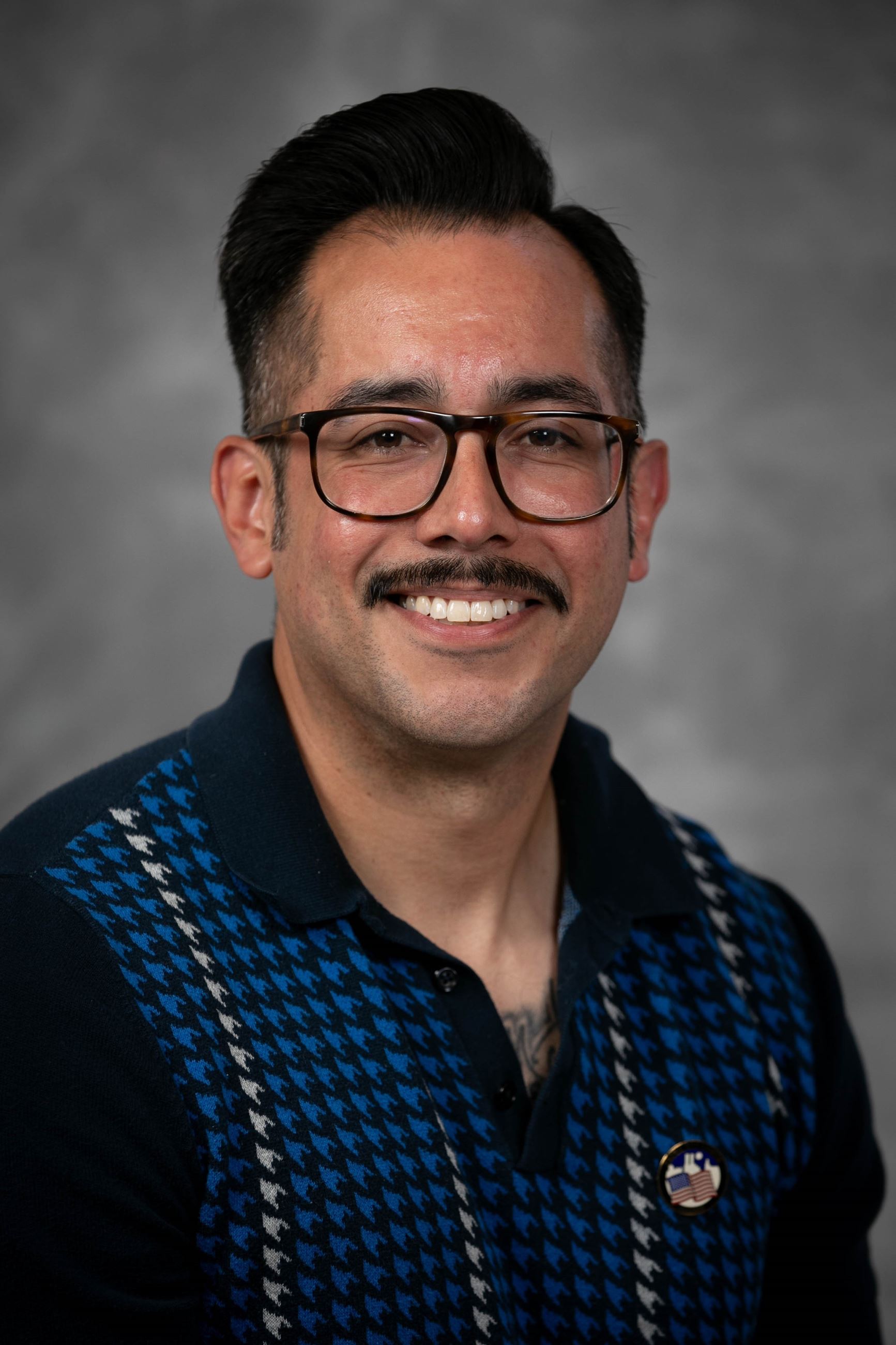 Headshot of a man wearing glasses and a sweater.