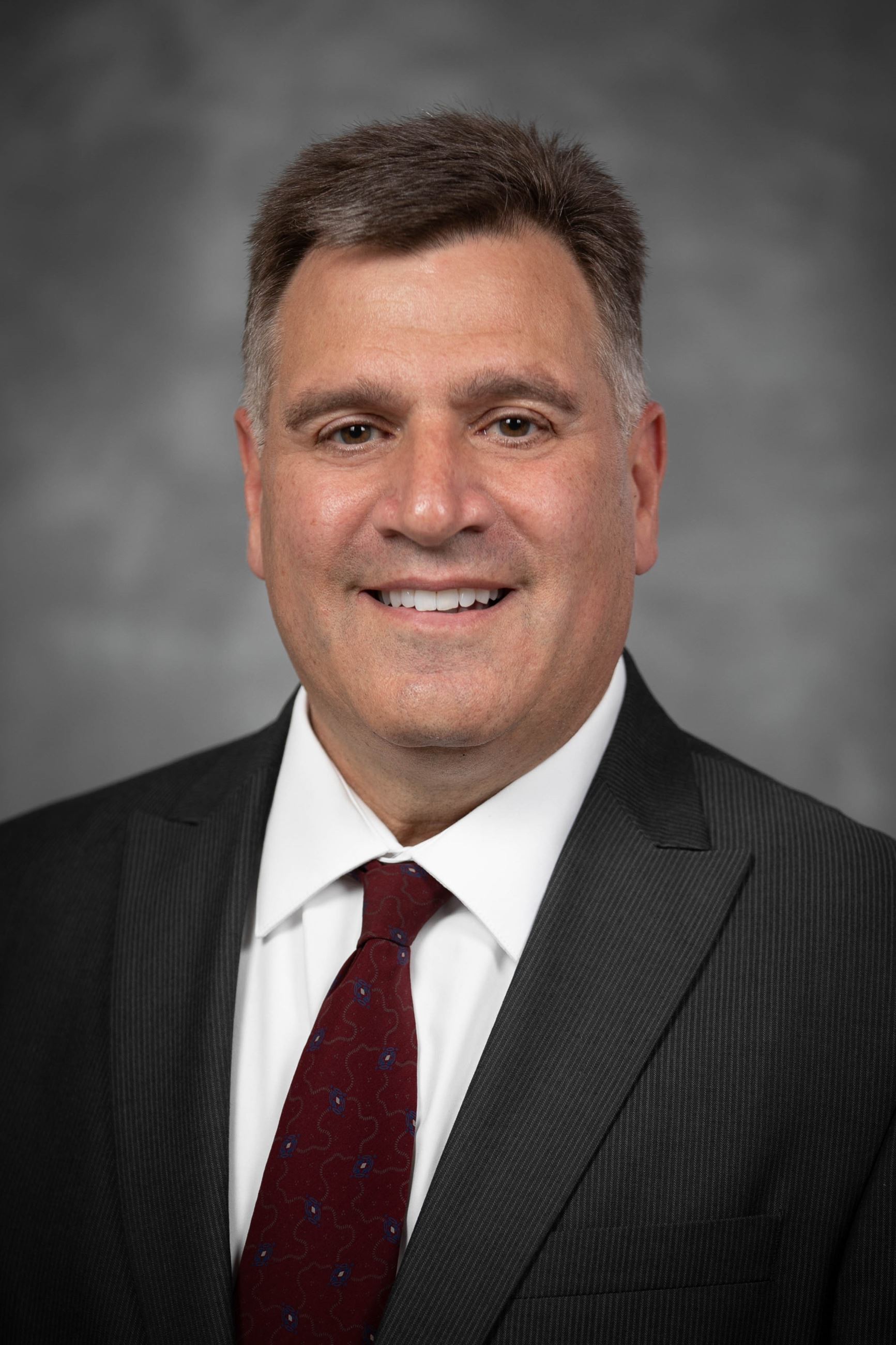 Headshot of a man in a coat and tie.